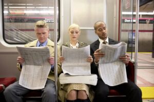 Three people on the train reading the newspaper