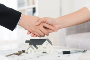 Small house model and two people shaking hands