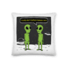 A pillow with two green aliens talking to each other.