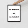 A person holding up a framed picture with the words are we human or are we coffee ?