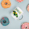 A coffee mug sitting on top of a table next to donuts.