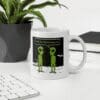 A white coffee mug with two green people on it.