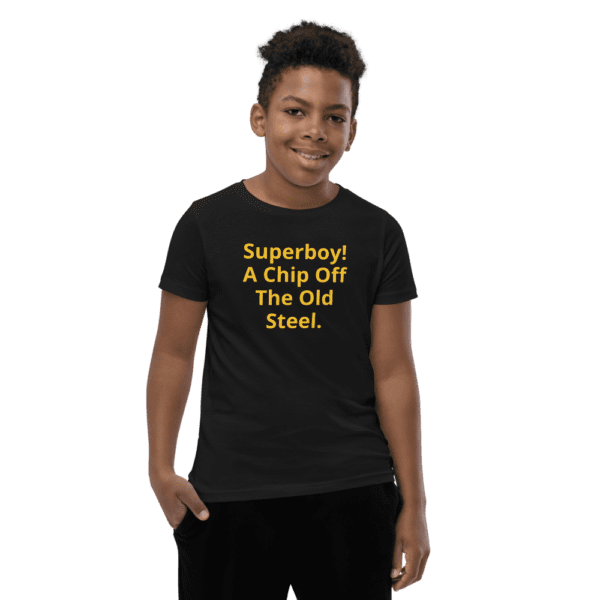 A boy wearing a black shirt saying Superboy! A chip off the old steel
