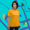 unisex-staple-t-shirt-gold-front-628f1d0882f2d A woman standing in front of a blue wall.