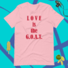 A pink shirt that says love is the g. O. A. T