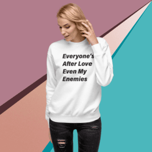 A woman wearing a white sweatshirt with the words " everyone 's after love even my enemies ".