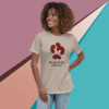 Smiling woman wearing a beige t-shirt with a red paw print and text design.