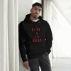 Man wearing a black hoodie with red text, posing indoors by a window.