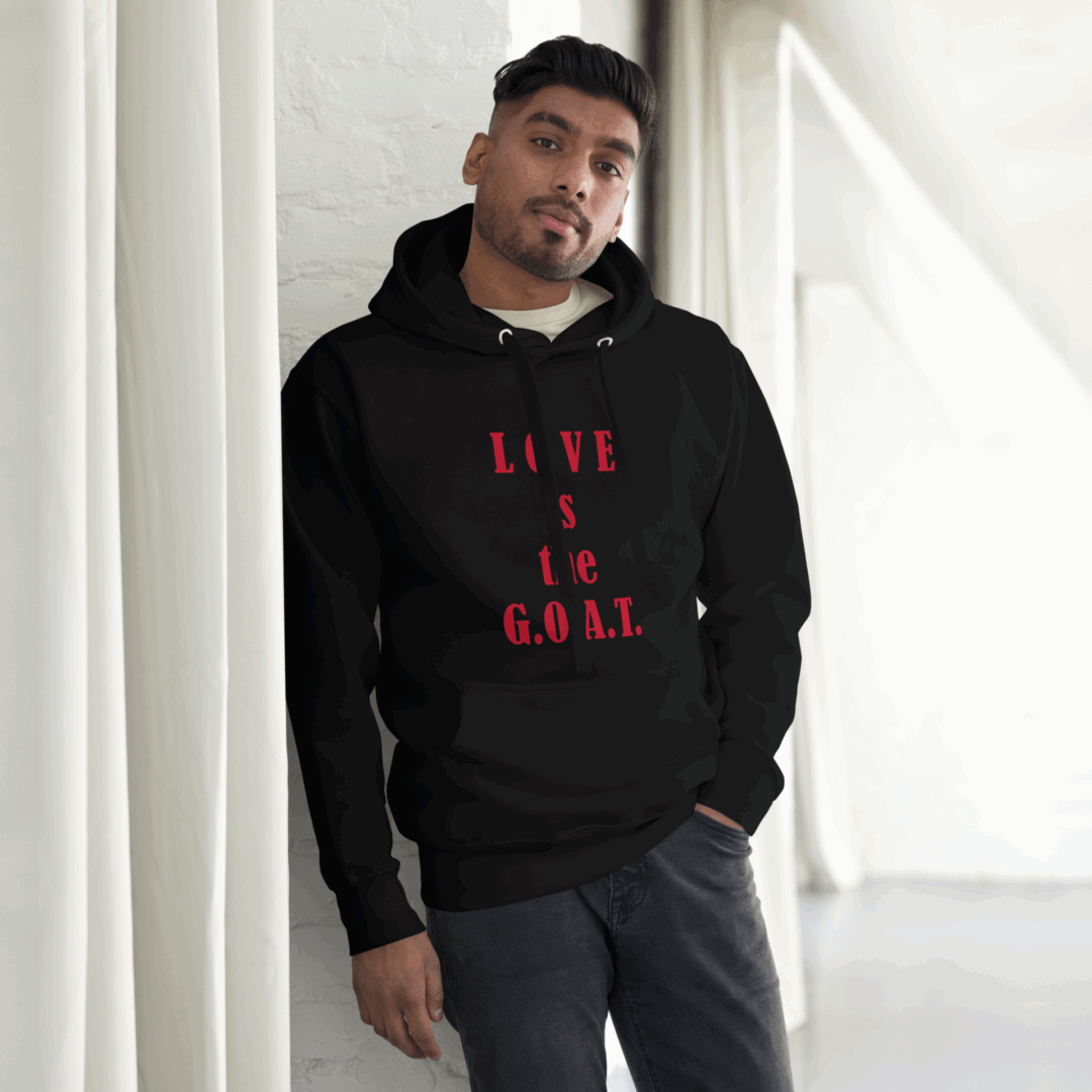 Man wearing a black hoodie with red text, posing indoors by a window.