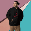 Man wearing a black hoodie with red text stands against a colorful geometric background.