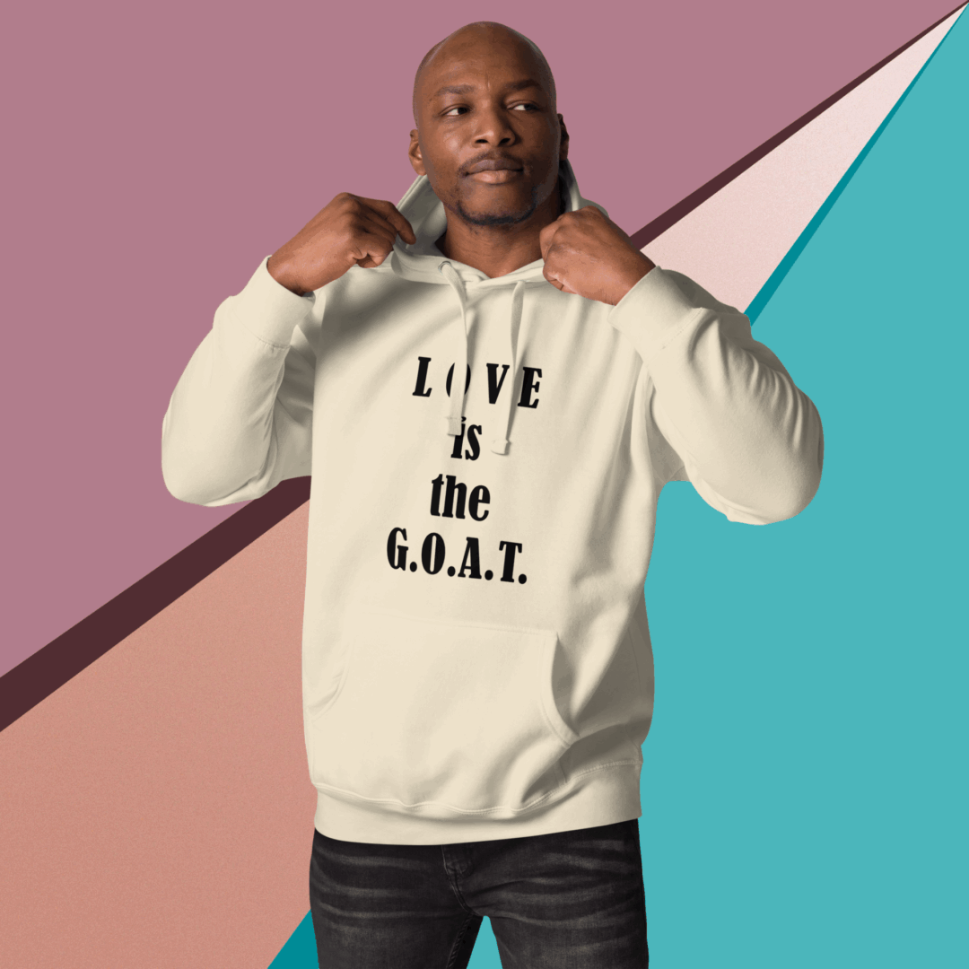 Man wearing a cream hoodie with the text 'LOVE is the G.O.A.T.'