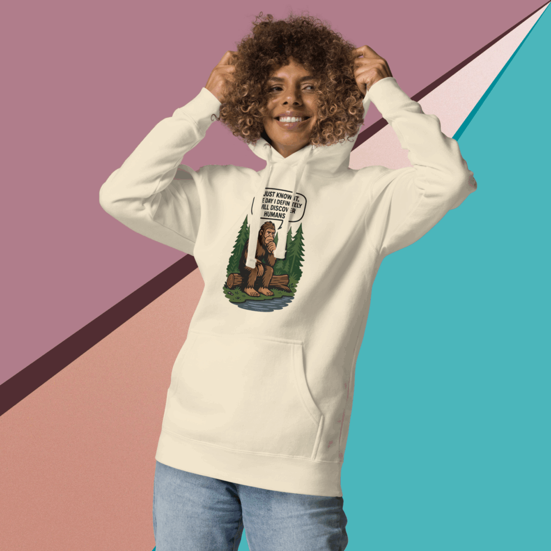 Smiling woman in a cream hoodie with graphic design and jeans.