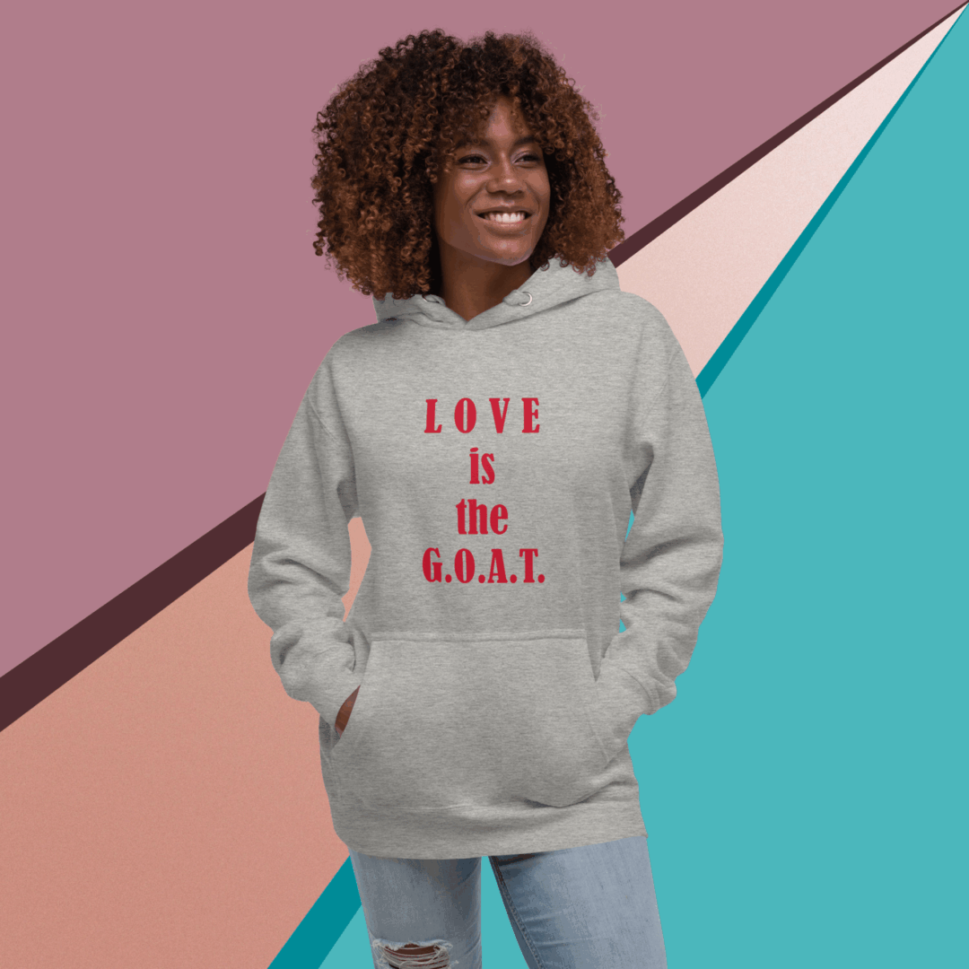 A woman smiling in a gray hoodie with the phrase "LOVE is the G.O.A.T."