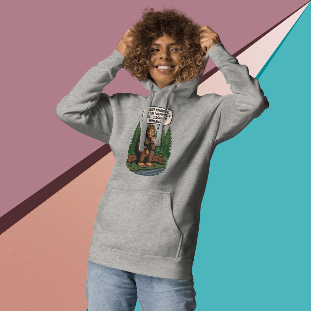 Smiling person in a gray hoodie with graphic design, posing against a colorful geometric background.