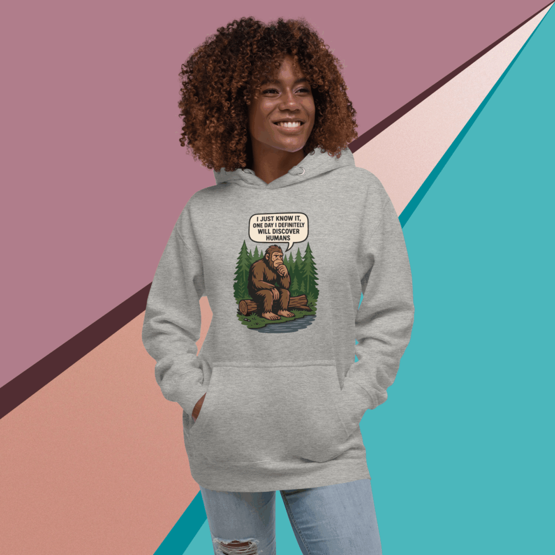 A smiling woman in a gray hoodie with a bear graphic stands against a colorful geometric background.