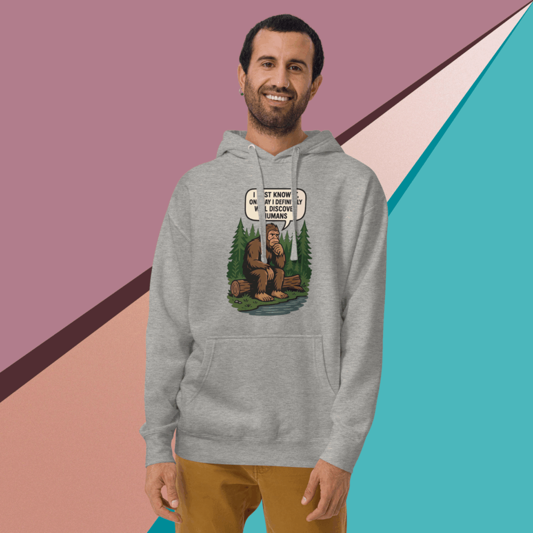 Man wearing a gray hoodie with a colorful graphic design, smiling against a geometric background.