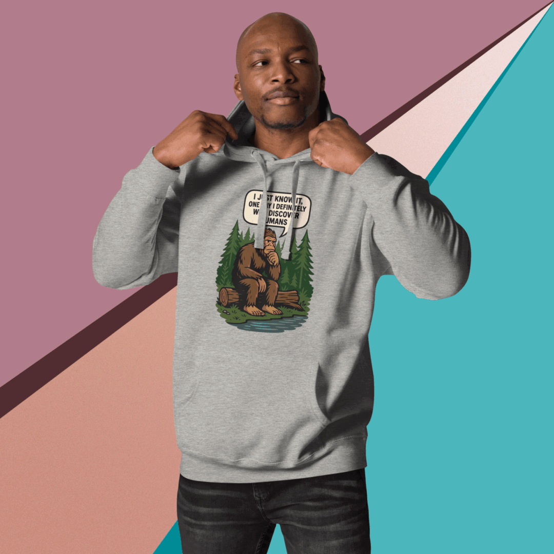 A man in a gray hoodie posing against a colorful geometric background.