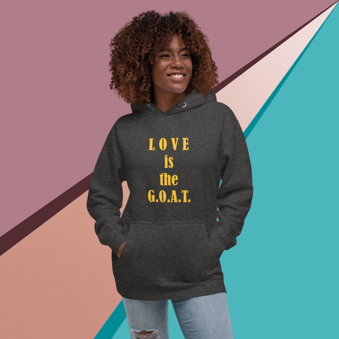 A woman wearing a hoodie saying 'LOVE is the G.O.A.T.' smiling.