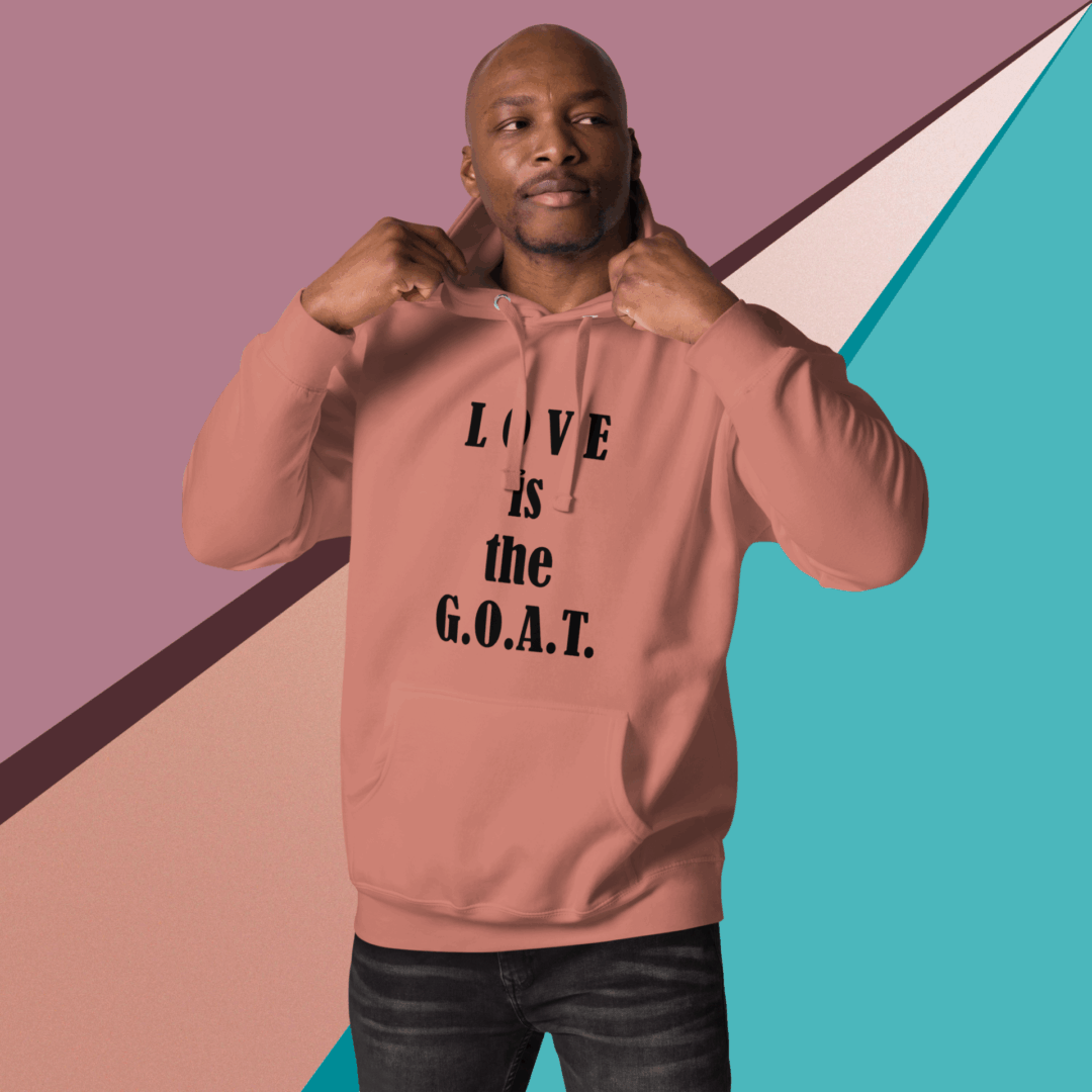 Man wearing a pink hoodie with the phrase 'LOVE is the G.O.A.T.'
