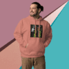 Man in a pink hoodie with graphic design, standing against a geometric colorful wall.