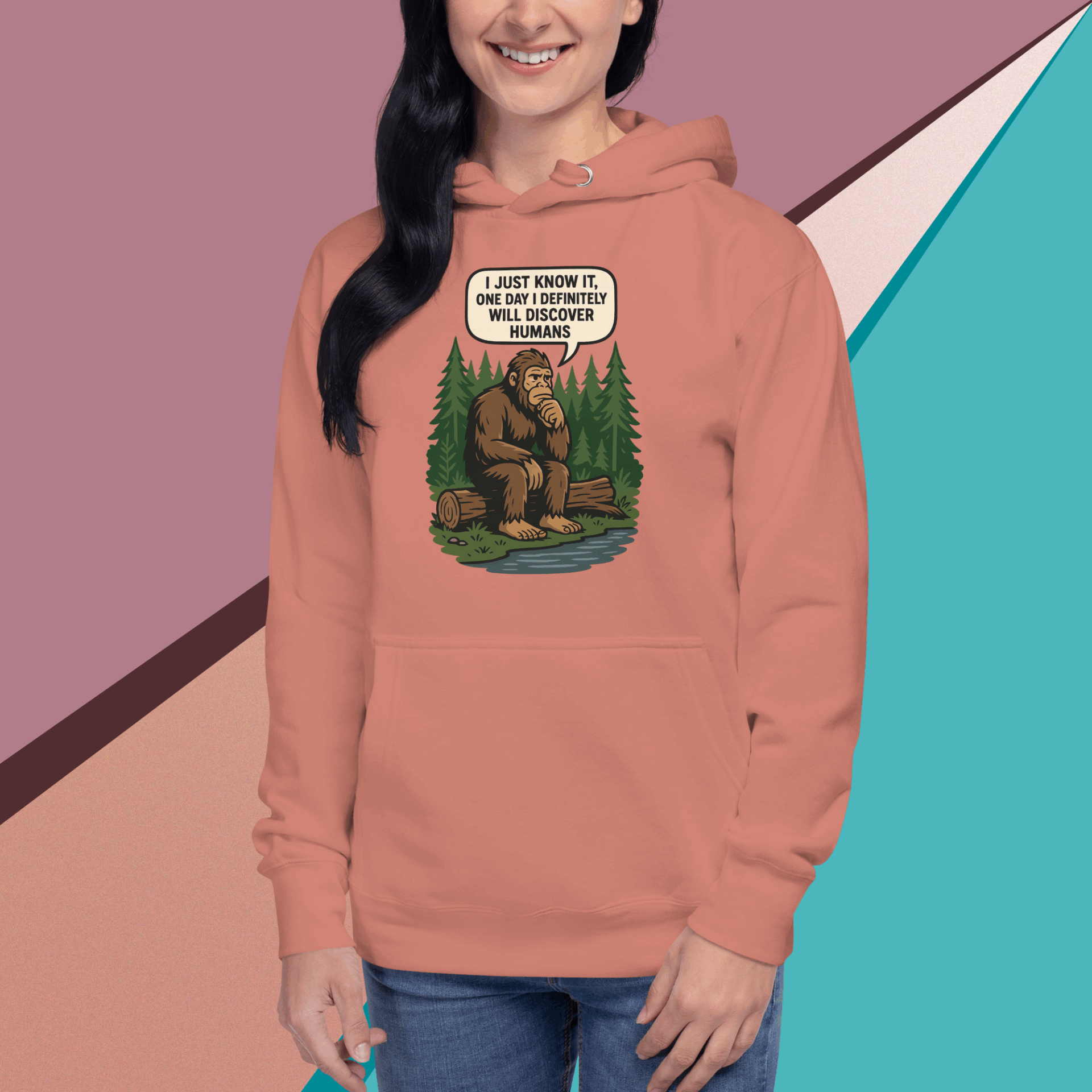 A woman wearing a pink hoodie with a Bigfoot cartoon and saying, "I don't believe in humans."