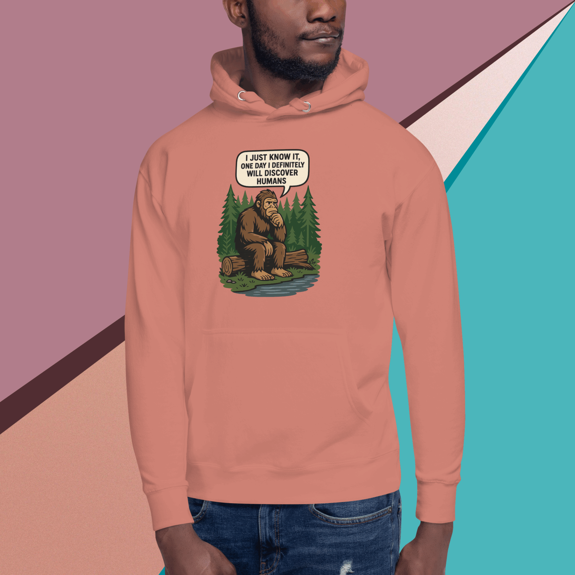 Man wearing a peach hoodie with a bear and forest design.