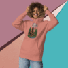 Smiling woman in pink hoodie posing against a colorful geometric background.