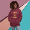 A woman wearing a maroon hoodie with 'LOVE is the G.O.A.T.' text.