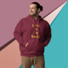 Man wearing a maroon hoodie with text, standing in front of a colorful geometric background.