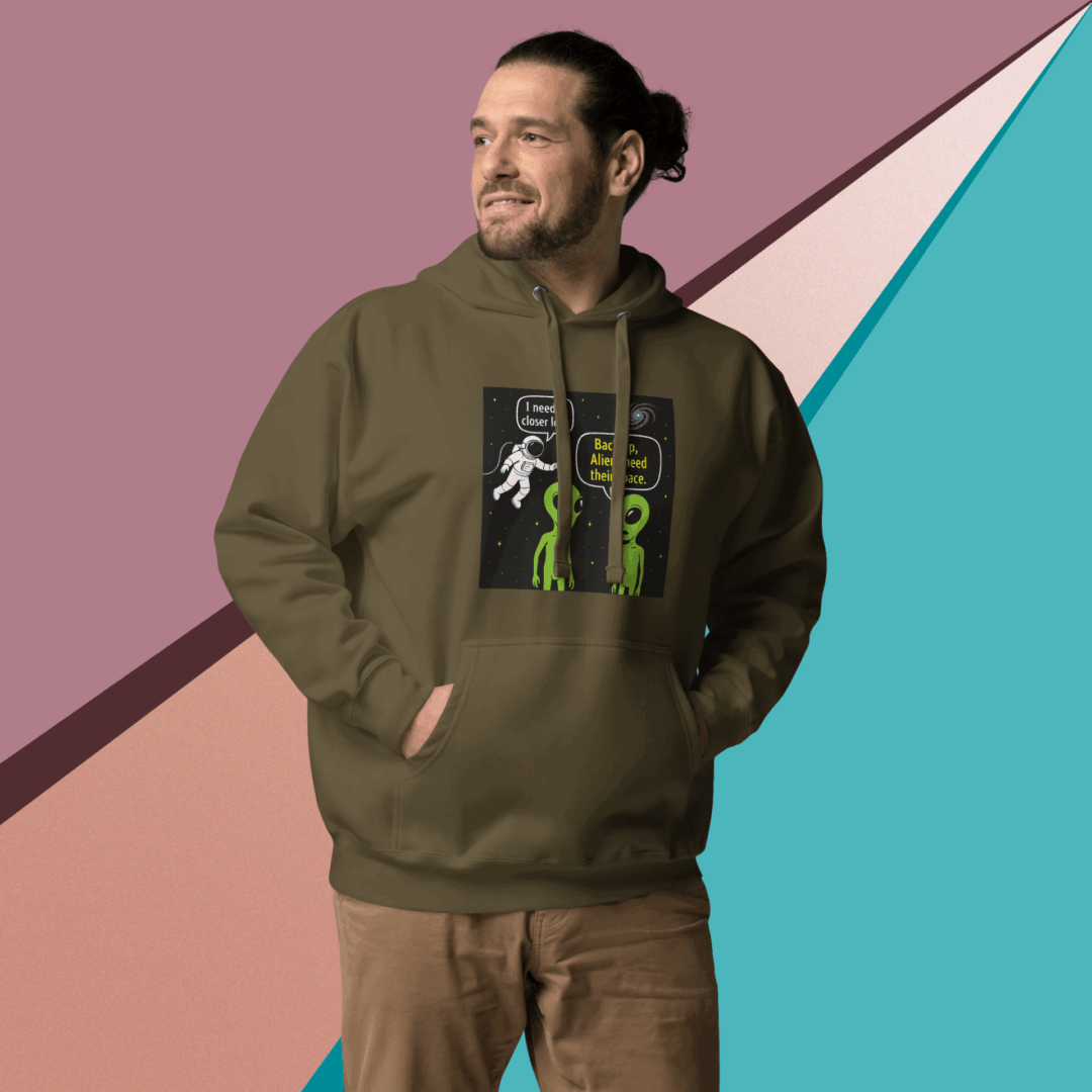 Man wearing an olive green hoodie with a graphic design, smiling and looking to the side.
