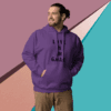 Man in a purple hoodie smiling against a colorful geometric wall.