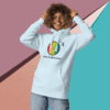 cotton-heritage-m2580-i-unisex-premium-pullover-hoodie-sky-blue-front-68e325432bc86 Smiling woman wearing a light blue hoodie with a colorful logo.