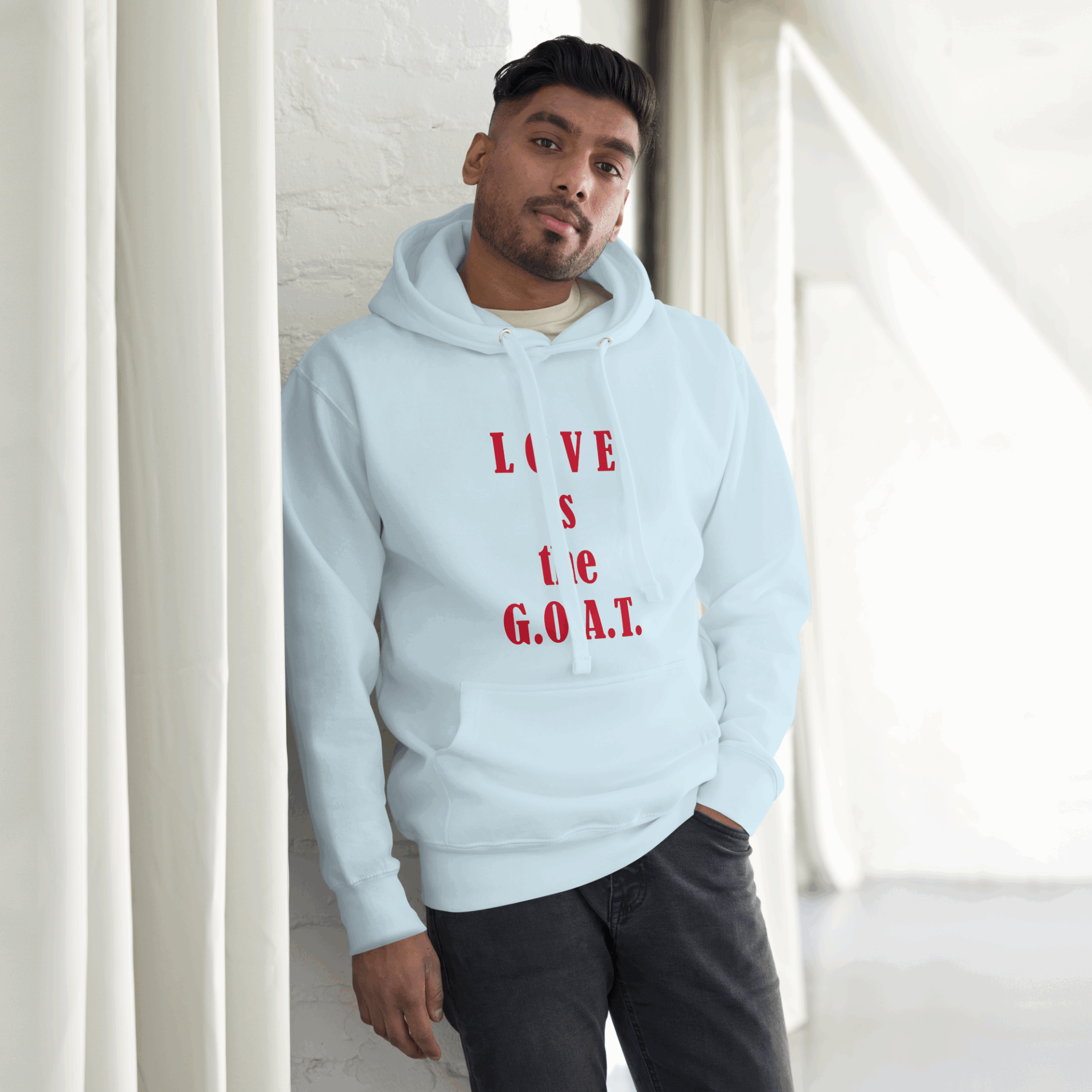 A man wearing a light blue hoodie with the phrase 'LIVE is GOAT'.