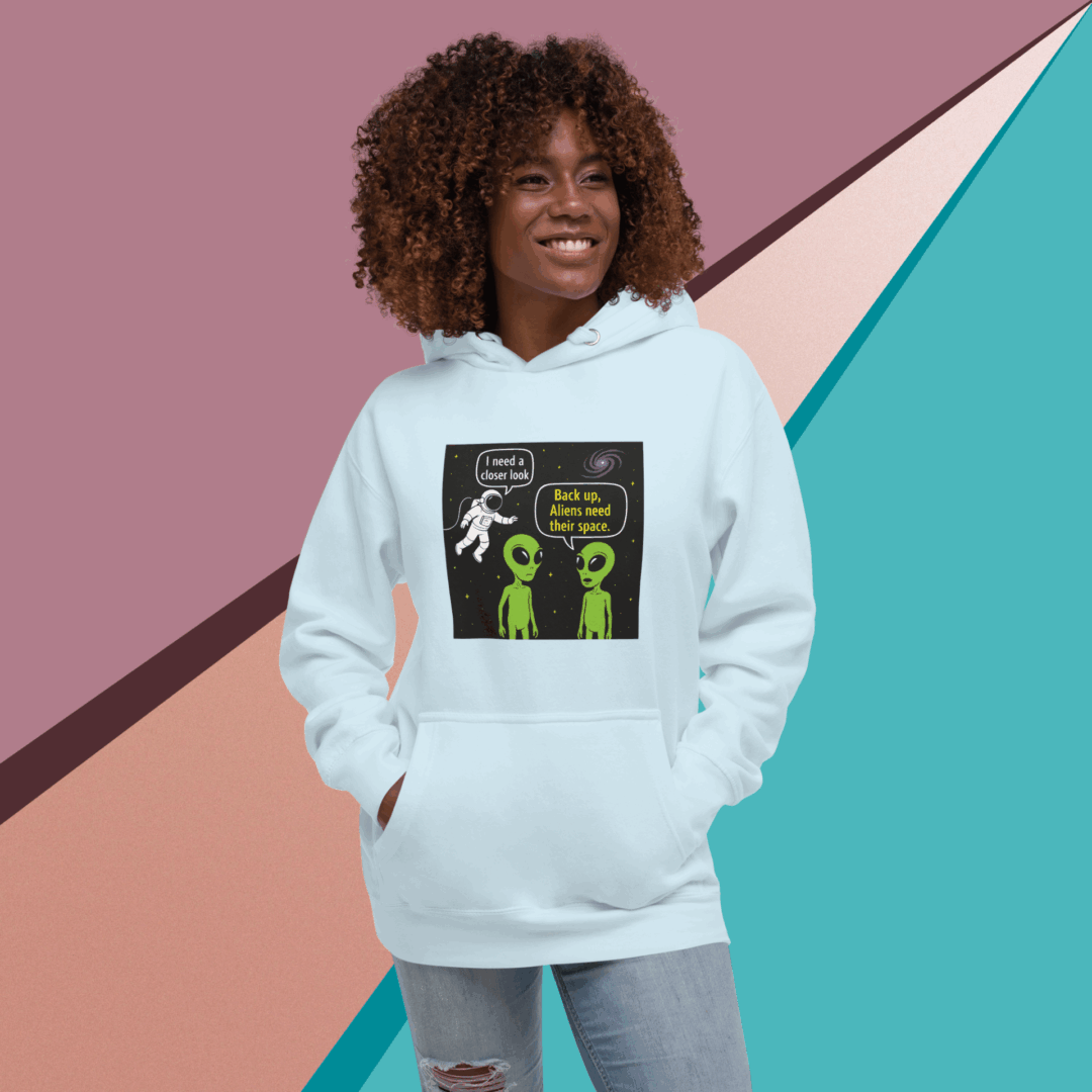 Smiling woman in a white hoodie with a graphic design standing against a colorful geometric wall.