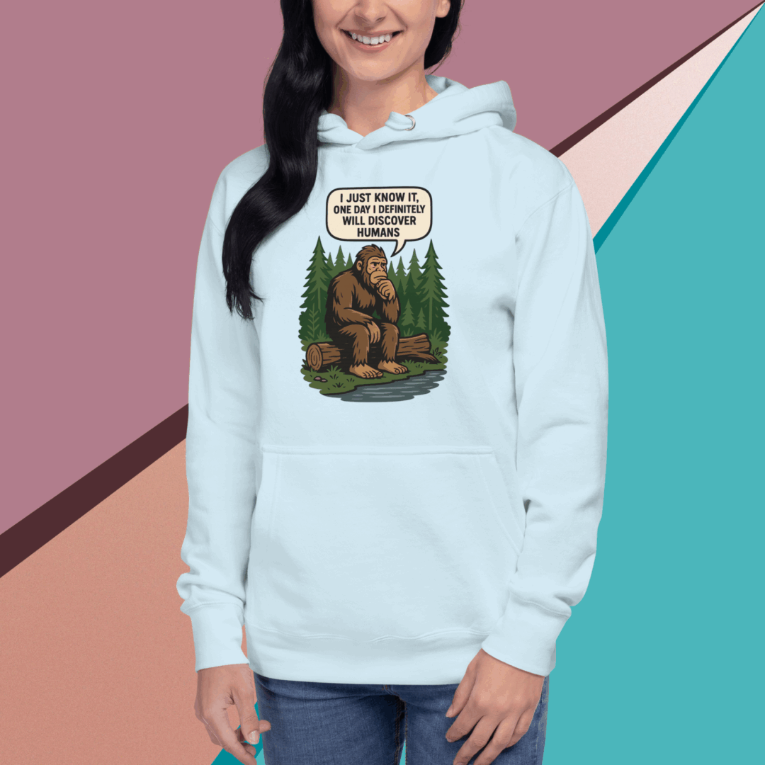 Woman in light blue hoodie with Bigfoot graphic and humorous text.