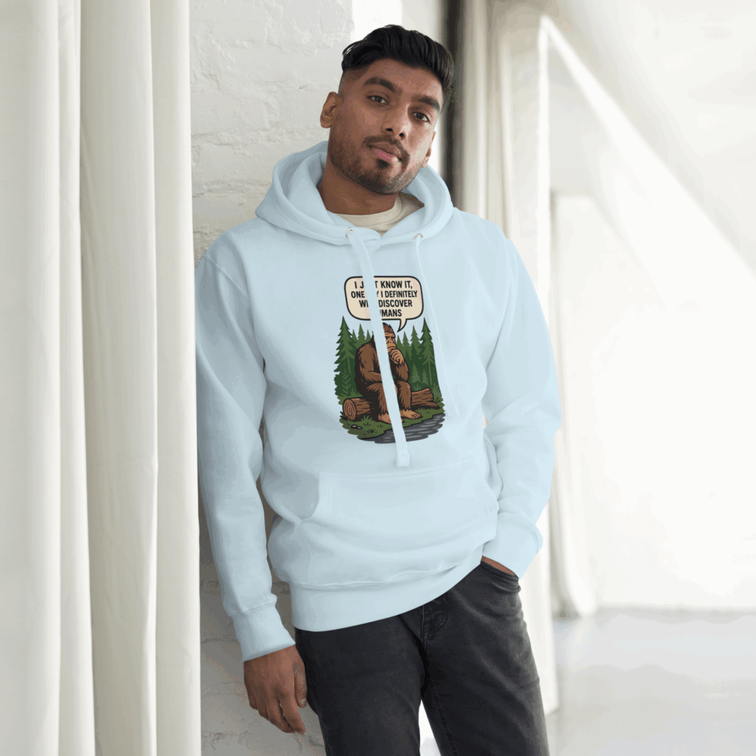 Man in light blue hoodie with a graphic print standing indoors.