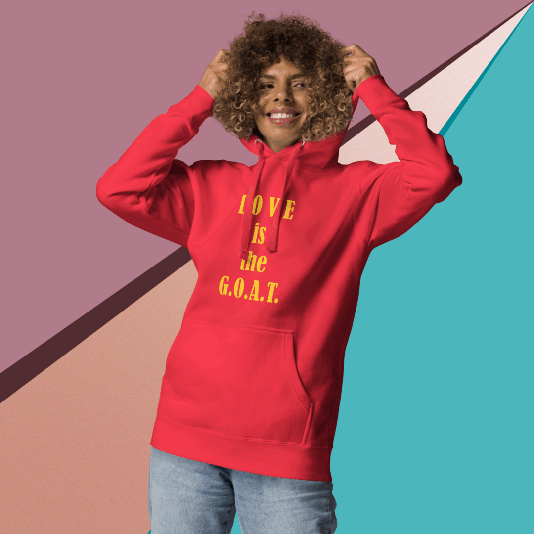 Smiling woman in red hoodie with text, posing against colorful backdrop.