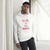 Man in white hoodie with red text leaning against a white wall.