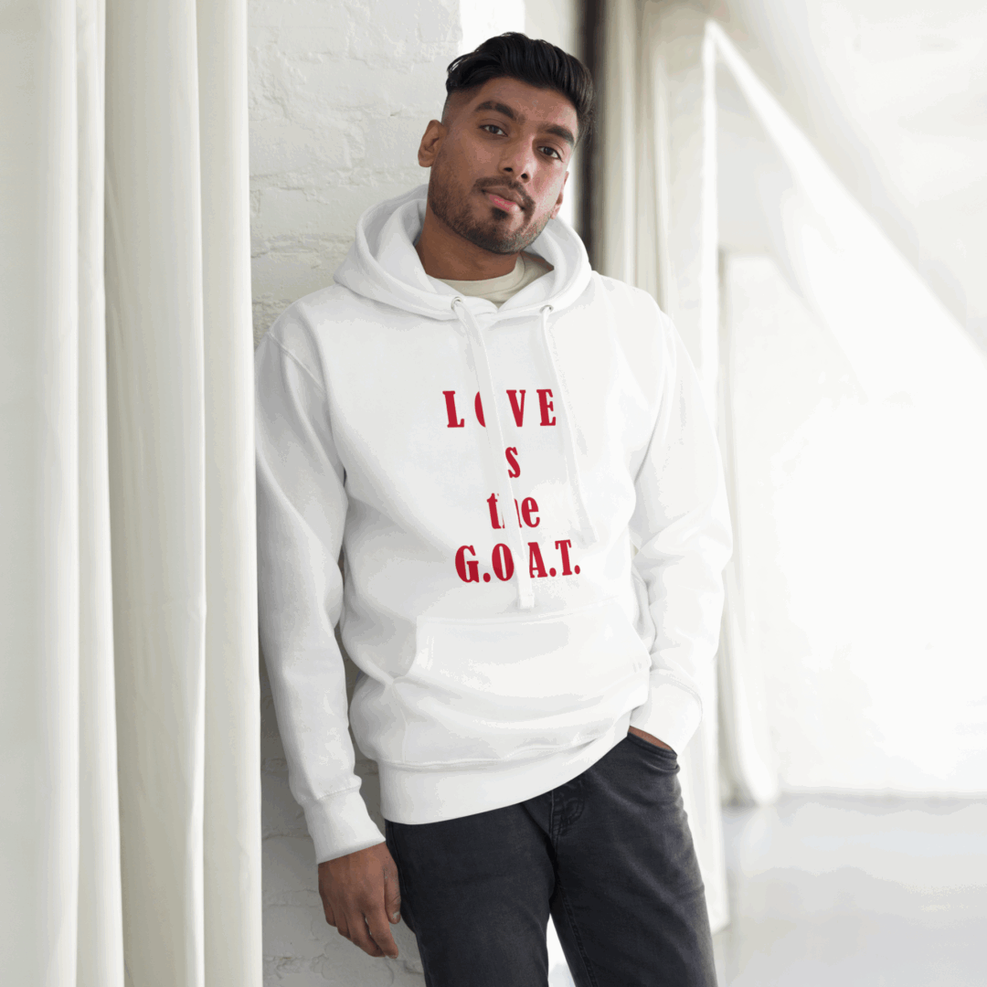 Man in white hoodie with red text leaning against a white wall.