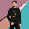 unisex-premium-sweatshirt-black-front-68f061351b380 Man in black sweatshirt with 'LOVE is the G.O.A.T.' text.