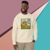 Smiling man wearing a cream sweatshirt with a cartoon dinosaur and text design.