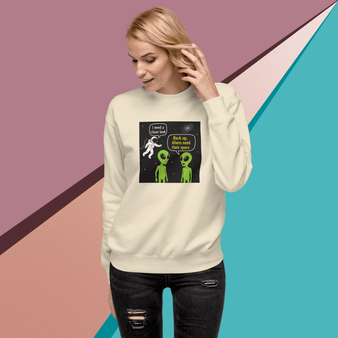 Woman wearing a cream sweatshirt with a humorous alien design.