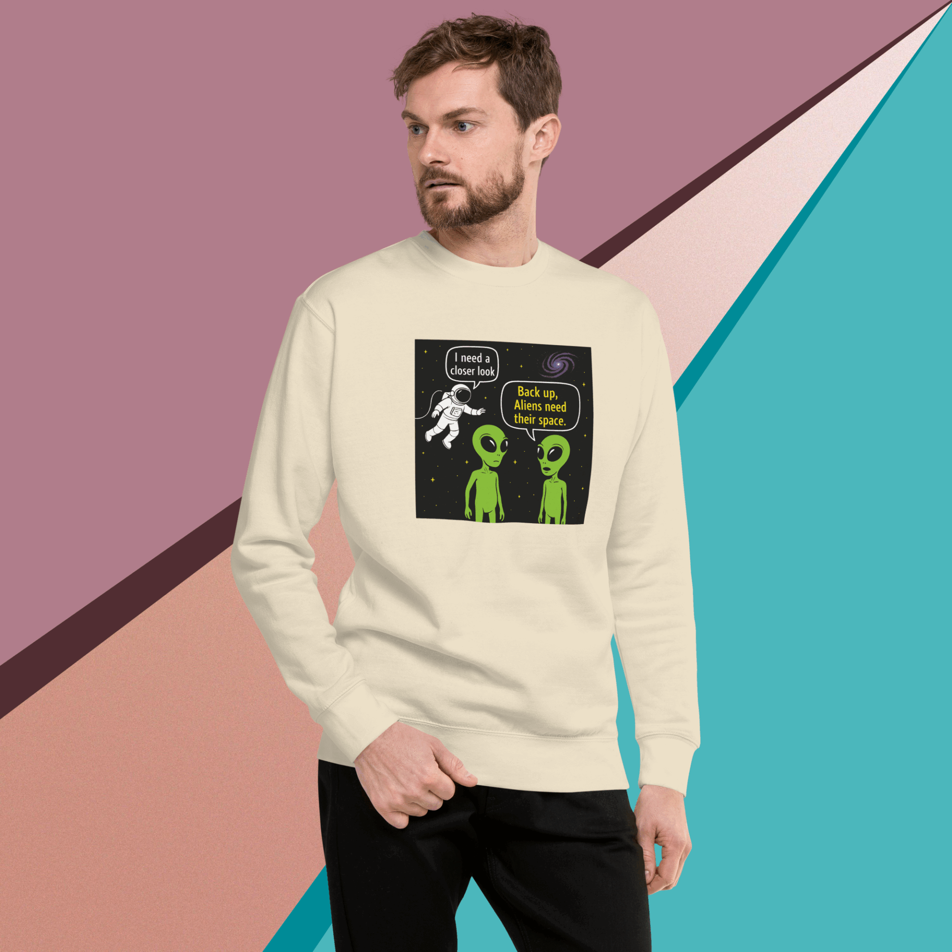 Man wearing a cream sweatshirt with a stick figure and aliens graphic.