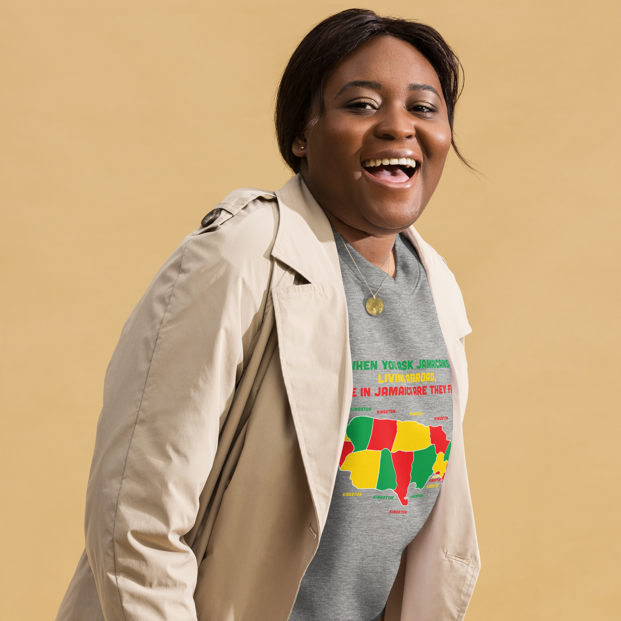 Smiling woman in a beige coat and colorful Jamaica-themed t-shirt.