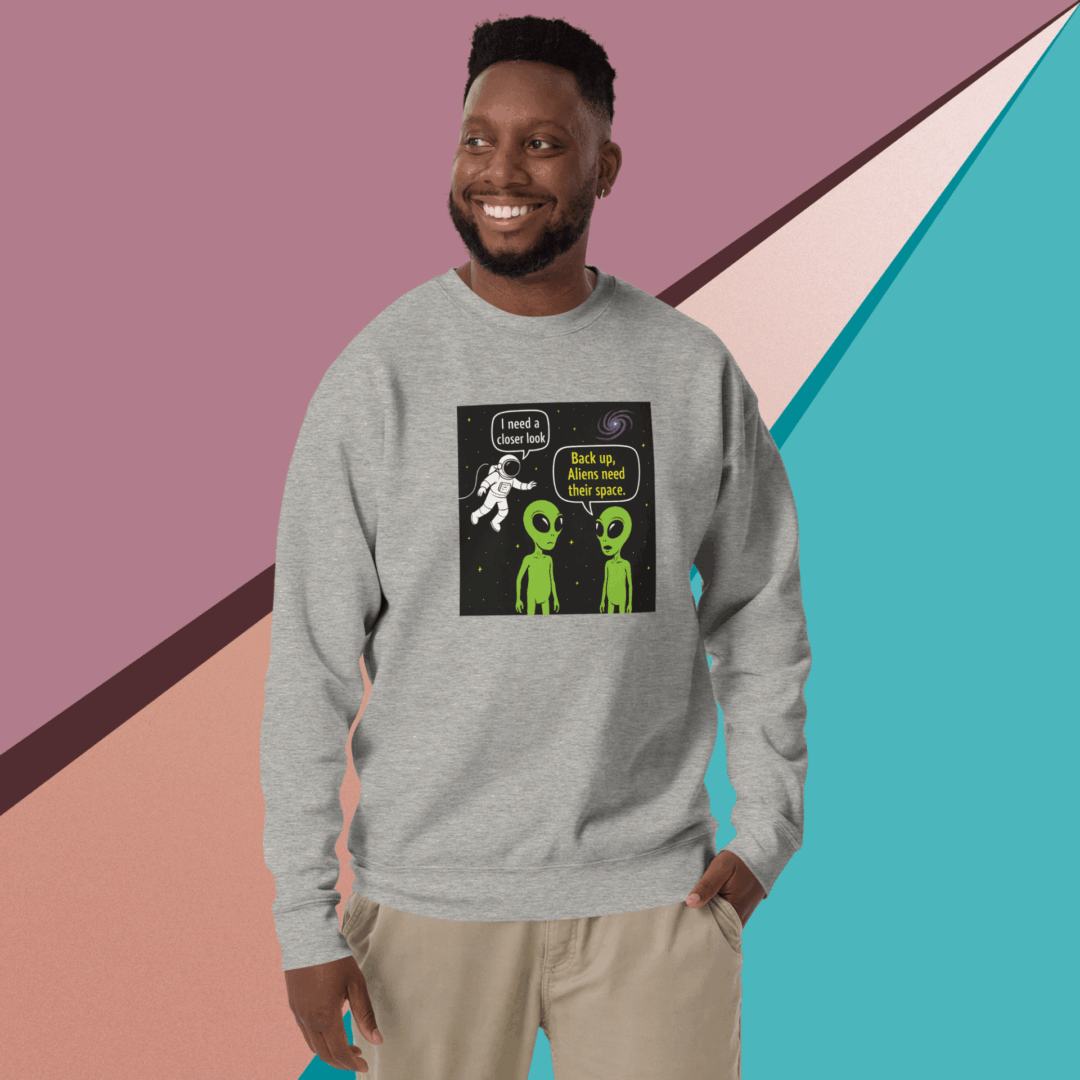 Smiling man wearing a gray sweatshirt with a graphic print, standing against a colorful geometric background.