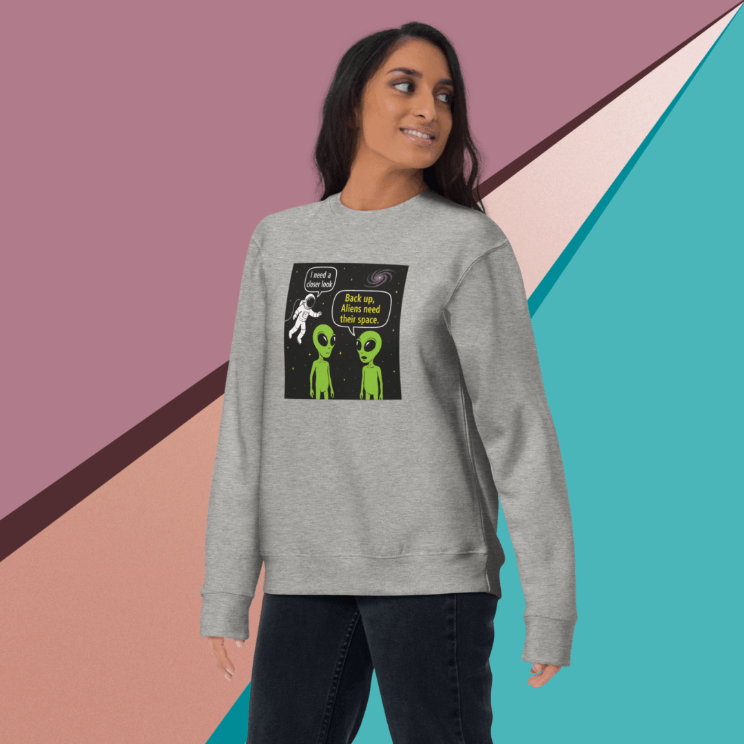 Woman wearing a gray sweatshirt with a colorful alien graphic.