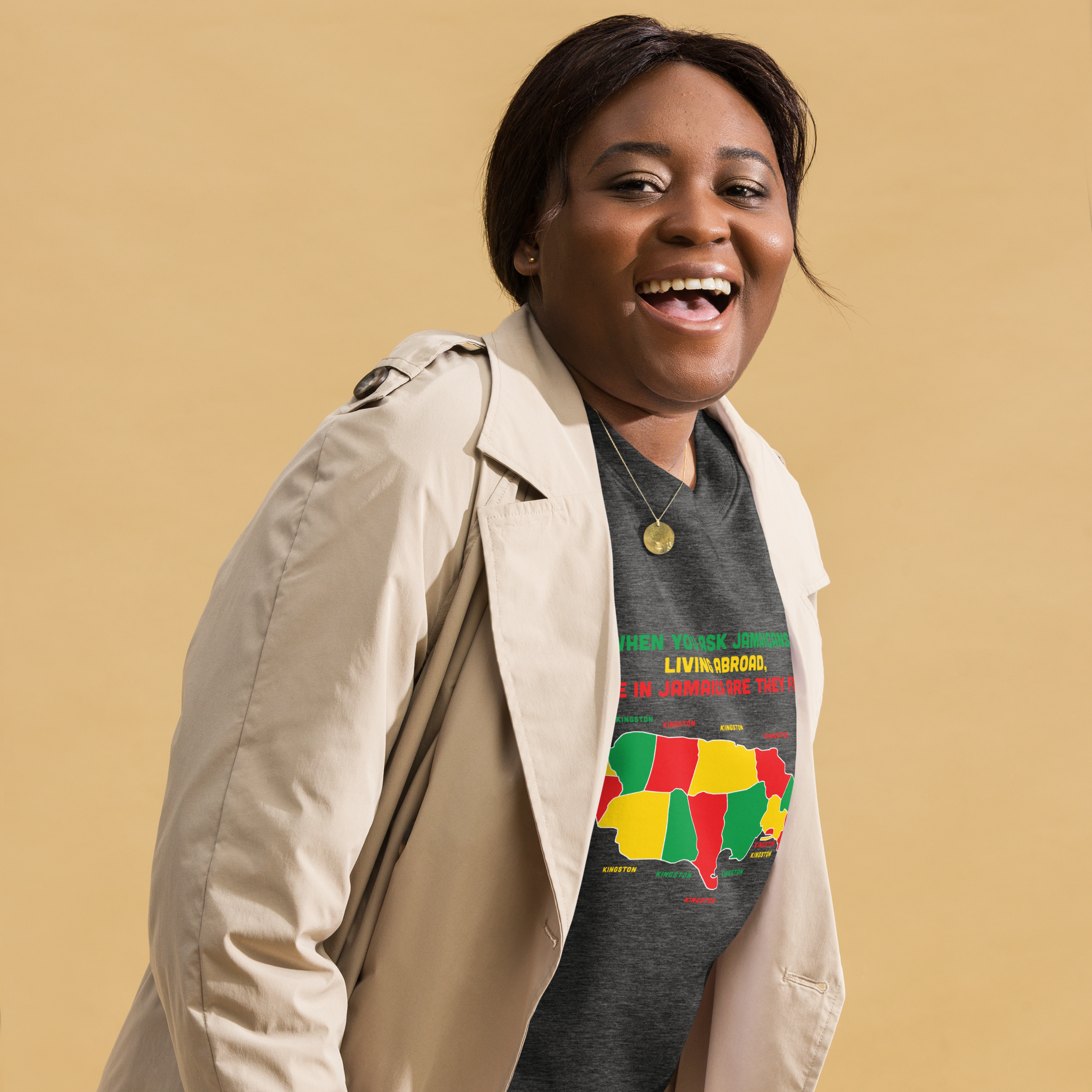 Happy woman laughing, wearing a beige coat and a colorful Jamaica-themed t-shirt.