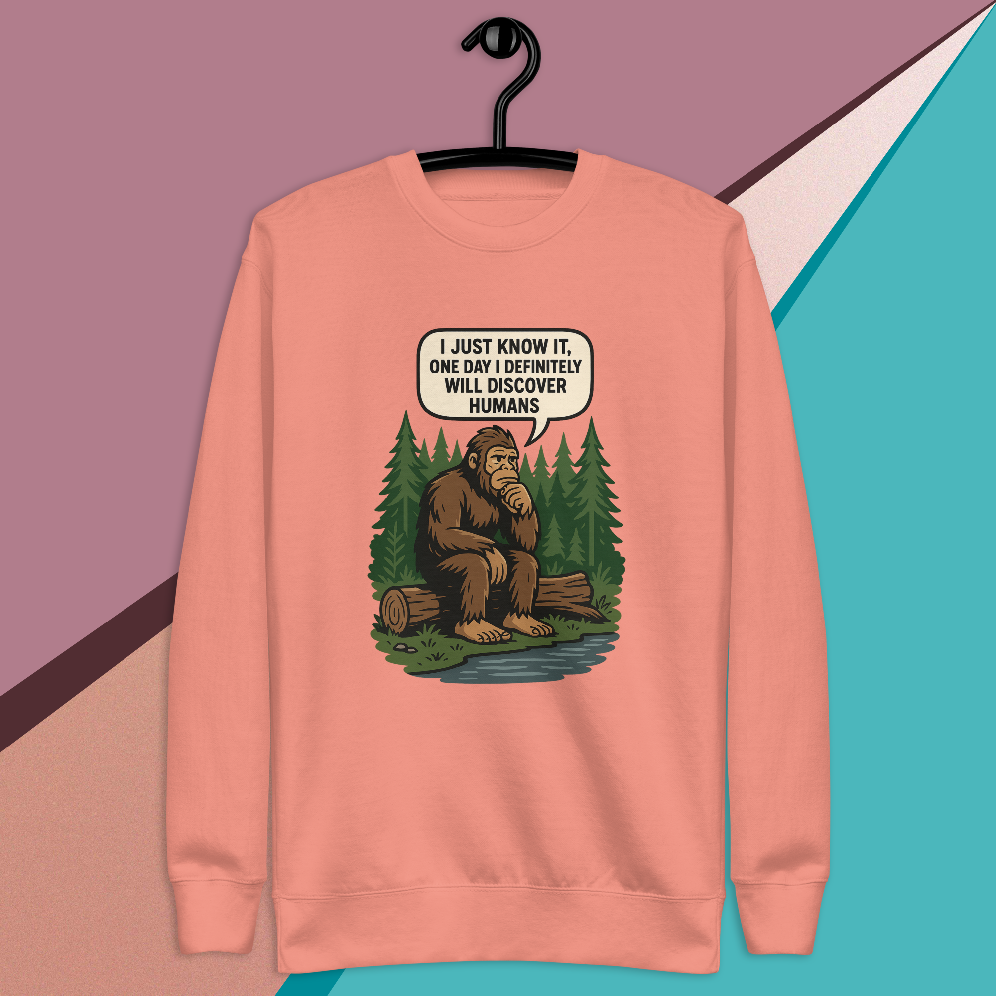 Peach sweatshirt with a sitting Bigfoot saying he'll discover humans.