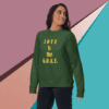 unisex-premium-sweatshirt-forest-green-front-68f061abc63e6 A woman wearing a green sweatshirt with 'LOVE IS the G.O.A.T.' text.