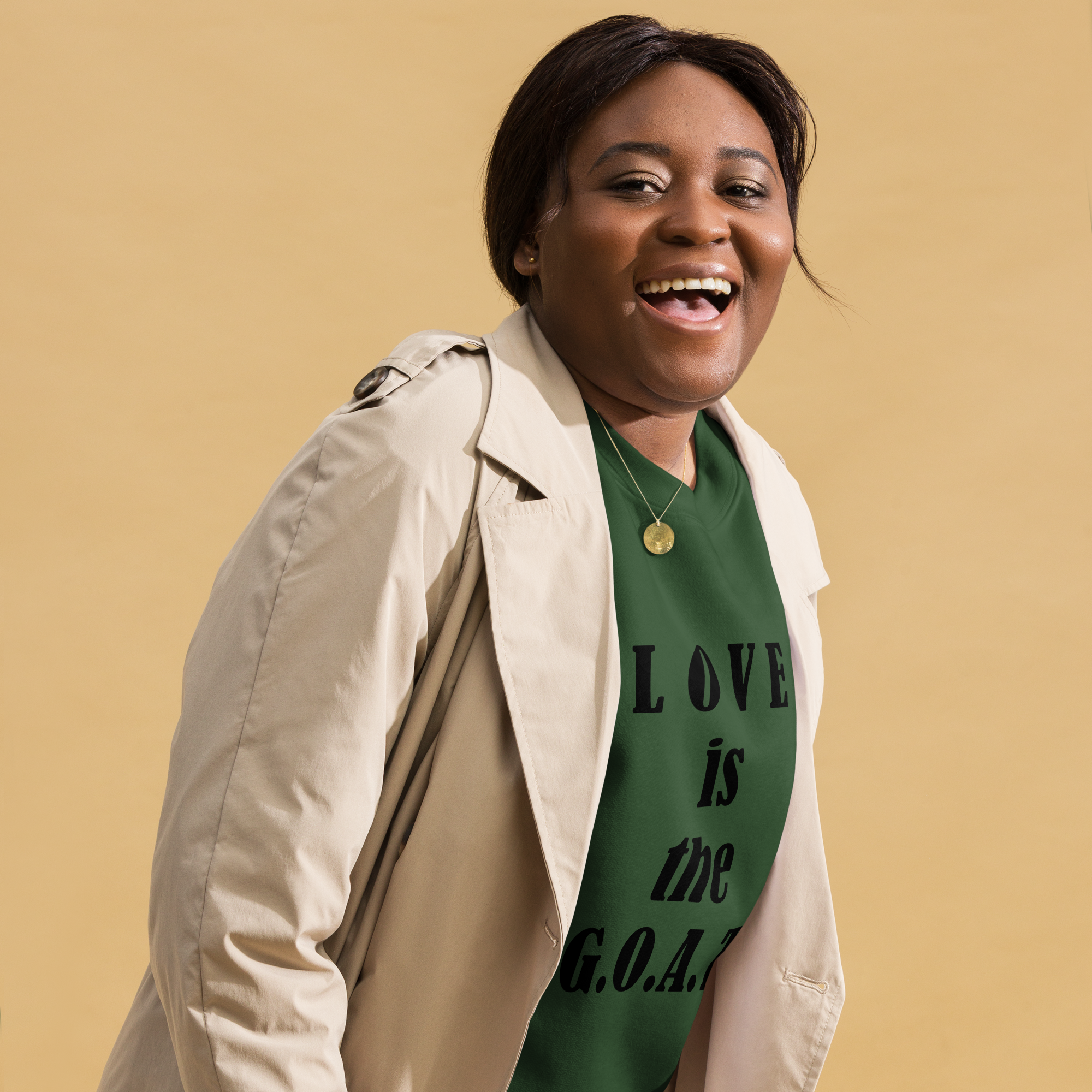 Smiling woman in a beige coat and green shirt with a positive message.